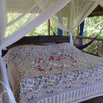 romantisch interieur boomhut van binnen met een groot twee persoonsbed en bloemetjes in de vorm van een hartje op het dekbed maffia eiland