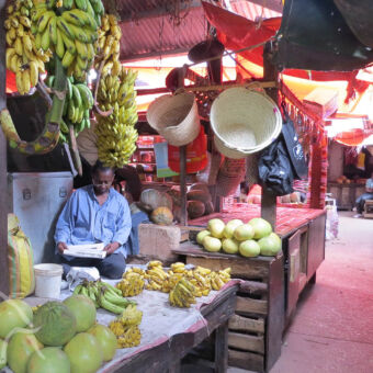 Darjani market verse meloenen, bananen en manden met zittende lezende man op de Darjani markt Stone Town zanzibar