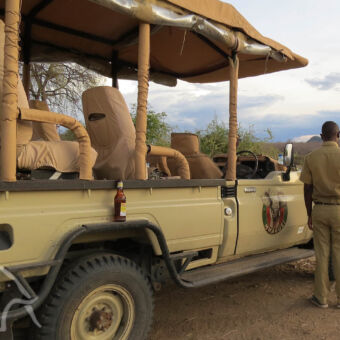 verfrissend drankje luxe open safariauto met een biertje op het spatbord tijdens een stop op gamedrive Zuid Tanzania