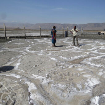 eeuwenoude stappen in de lava ondergrond twee mensen op het terrein van homonid footprint vlakbij lake natron tanzania