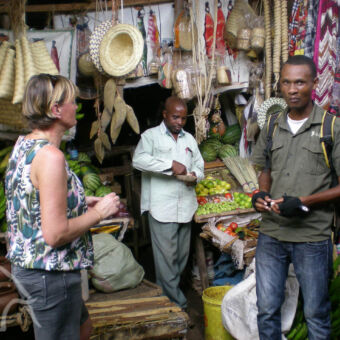 kleurrijke markt vrouw en gids en marktkoopman bij een kraam op de markt van mto-wa-mbu tanzania