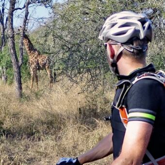 man met helm stilstaand kijken naar een giraffe in het bos bij arusha national park tanzania