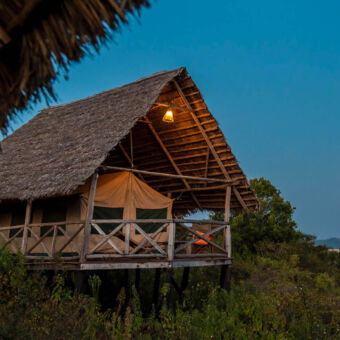 tent canvas tent met rieten dak op palen en een veranda van op een heuvel uitkijkend op rhotia valley tanzania