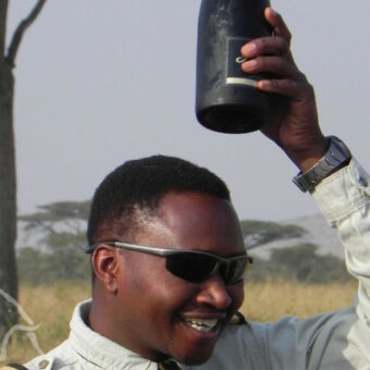 koude champagne! hoofd van man met bovenzijn hoofd een fles champagne in zijn hand voor de doop ceremonie na een ballonsafari op de serengeti
