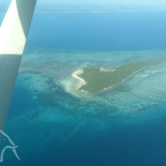 Indische oceaan met eilandje in een klein vliegtuigje met uitzicht op mafia eiland in de azuurblauwe indische oceaan