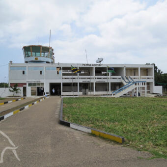 Pemba Island airport weg die naar een wit gebouw leidt die dienst doet als terminal bij het vliegveld van Pemba