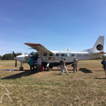 ready for take off kleine vliegtuigjes in Tanzania, airstrip met een vliegtuigje en verschillende mensen die net zijn aangekomen en een Fly-in safari naar de Serengeti hebben