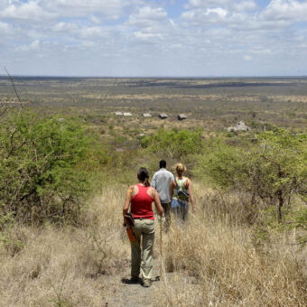 begeleide wandeling Lake Chala drie mensen die wandelen onder begeleiding door een gebied met struiken en hoog gras vlakbij lake chala in de buurt van de kilimanjaro tanzania