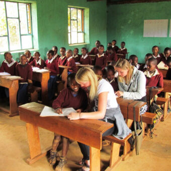 in de klas klas met jonge kinderen op safari en 50 leerlingen zittend in een schoolbank bij een bezoek aan een school cultuur activiteit tanzania