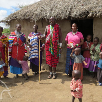 masai familie met ouders en kleine kinderen voor hun boma in de omgeving va de ngorongoro