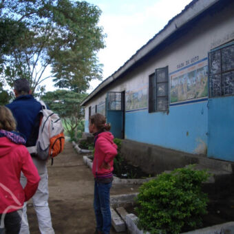 bezoek primary school man met kinderen buiten de klaslokalen van een Tanzaniaanse school