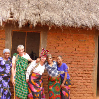 vrouwen en toeristen in traditionele kleding tijdens een excursie in een dorp in tanzania