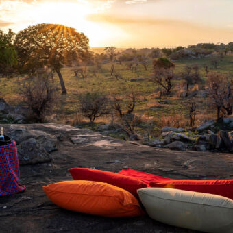 romantische sundowner champagne en kleedjes en een uitzicht over de serengeti waar de zon ondergaat