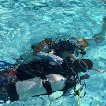 Duikles op Pemba eiland Duiken Pemba Tanzania. Twee duikende mensen waarvan een les krijgt.