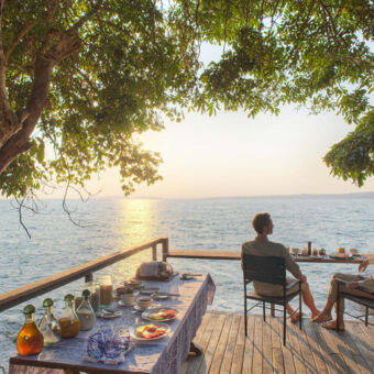 Rubondo Island Camp ontbijt waarbij je over Lake Victoria kijkt zittend jong stel aan het ontbijt uitkijken over lake victoria romantisch rubondo eiland camp tanzania huwelijksreis
