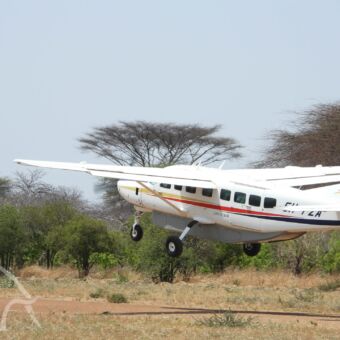 klein vliegtuigje om van park naar park te vliegen klein wit vliegtuigje dat net is opgestegen nog boven de airstrip luxe fly-in safari tanzania