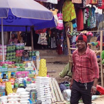 tanzaniaanse markt met kraampje vol schoonmaakspullen en de verkoper