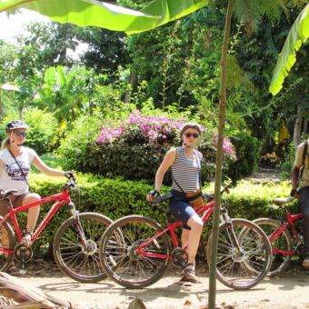 twee ouder meiden stilstaand met mountainbike en gids excursie mountainbiken tanzania