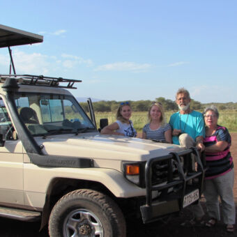 familie met twee oudere kinderen bij de stoere 4x4 met open dak familie reiservaring tanzania
