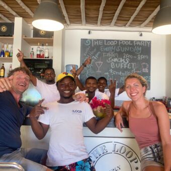 vrolijk lachende groep mensen aan de bar en achter de bar tijdens huwelijksreis zanzibar