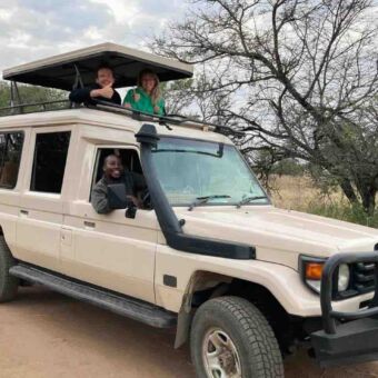 safari auto met het dak omhog waar een man en een vrouw hun duimen opsteken