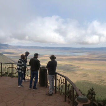 Uitzicht over de Ngorongoro krater in Tanzania. Een van de 7 wereld erfgoederen. Safari Tanzania rondreizen ter inspiratie. Bij het uitzichtpunt van Ngororongoro krater kijken mensen en hun gids de Ngorongoro krater in. Een panoramisch uitzicht over de krater.