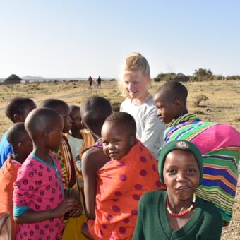 Tanzaniaanse kinderen met een dochter van een familie op safari door Tanzania