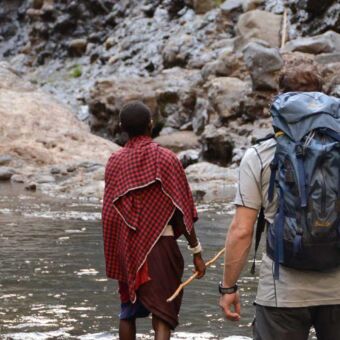 mensen die je van achterzijde ziet lopen bij de rotsachtige rivierbedding van de ngare sero rivier