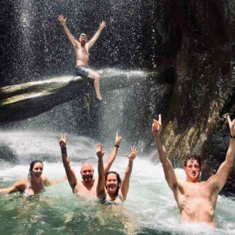 blije mensen met handen omhoog bij de ngare sero waterval