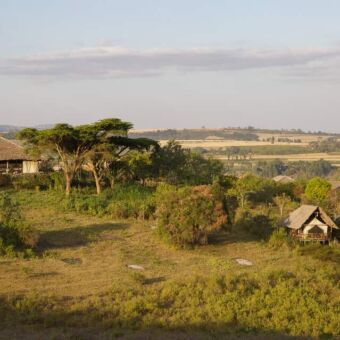 lanschapsfoto bij Rhotia valley tanzania met het glooiende landschap en de lodge met tented camp tanzania