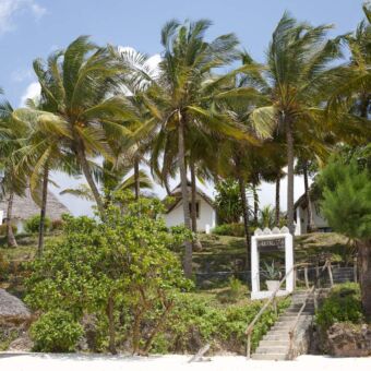 uitzicht vanaf het strand op de shooting star lidge met wuivende palmen en de witte huisjes