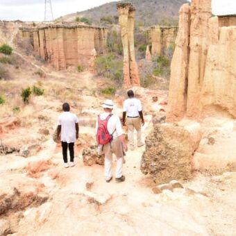 man en gids wandelen door isimilia stone age bij iringa tussen de hoge zandsteen pilaren