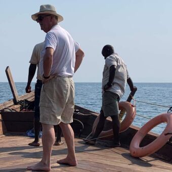 drie mannen staand op een houten boot uitkijken over lake tanganykia tanzania