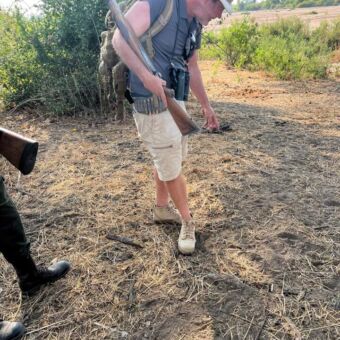 man met geweer tijdens een wandelsafari die op zoek is naar sporen van dieren in ruaha national park tanzania