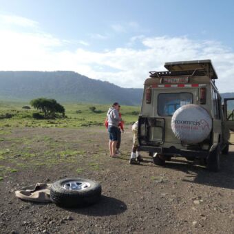 een safari auto van droomreis tanzania met een lekke band die ze aan het vervangen zijn