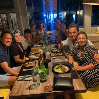 10 gasten van droomreis tanzania aan een lange tafel tijdens een diner gemaakt door hun eigen privé kok op het eiland zanzibar