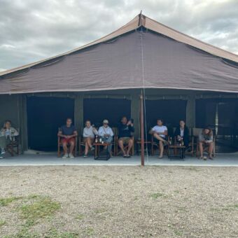 grote diner tent met daarvoor allemaal gasten van droomreis tanzania die daar een drankej doen