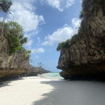 doorkijk vanaf het strand langes een grote rots naar de indische oceaan