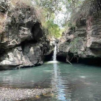 Heldere beek tussen rotsen met achteraan een waterval