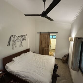 in een kamer van arusha villa waar een groot bed staat en aan de witte want zie een grote gnoe gemaakt van draadstaal