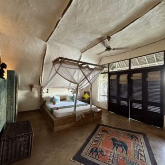 overzicht van een kamer met een groot bed, witte kalkmuren en plafond verder gedecoreerd met strandmaterialen bij sunshine marine lodge