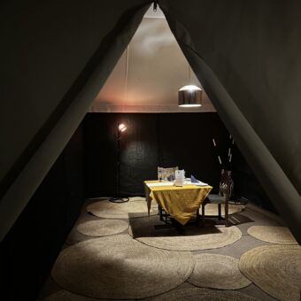een tafel met twee stoelen in een safaritent die schemerig verlicht is voor een privédinner