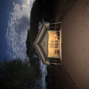 grote safari tent van voren met de lichten binnen aan en twee stoelen ervoor