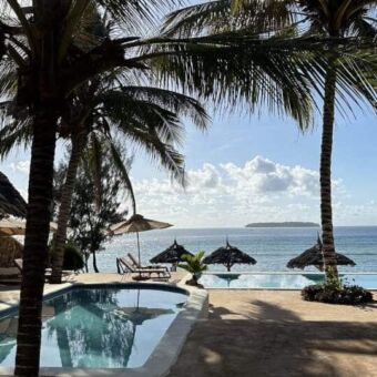 Rondreis Tanzania. Uitzicht met prachtige palmen, een zwembad en daarachter de indische oceaan bij sunshine marine lodge zanzibar.