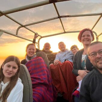 selfie van 7 reizigers die op een safari rondreis zijn door Tanzania. Ze zitten in een open safari auto