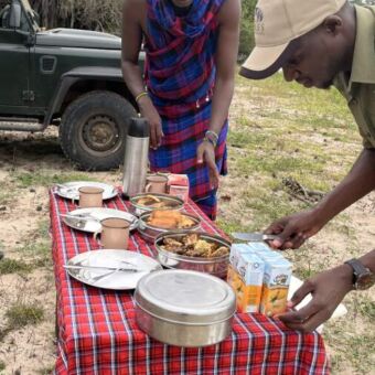 twee Tanzaniaanse gidsen die eenlbush lunch klaar zetten op een tafel midden in Ruaha national park