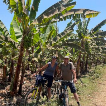 Twee gasten van Droomreis Tanzania die stilstaan met hun mountainbikes tussen de bananenplantages in Mto wa Mbu Tanzania