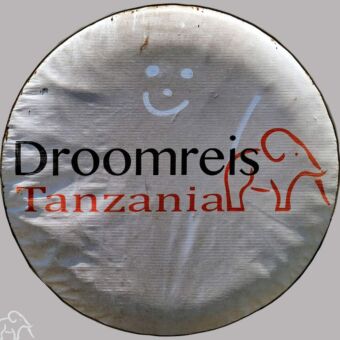 Uitgelicht de hoes van Droomreis Tanzania om een autoband op de safariauto van Droomreis Tanzania. Op de vieze hoes is een smiley getekend door de gasten. Review Droomreis Tanzania