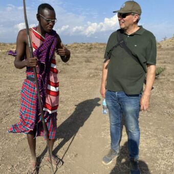 Rondreis Tanzania. Wandeling met een Masai. Een man en een Masai krijger lopen over de vlakte in het dorre landschap tijdens een safari in Tanzania