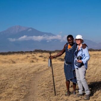 Activiteit wandelen met een Masai. Vrouw en Masai staan in de open vlaktes te poseren. Reisverslag Tanzania